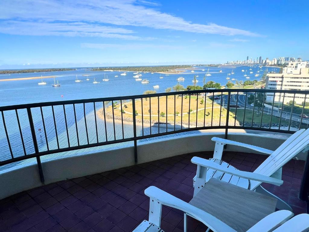 a balcony with two white chairs and a view of a harbor at Broadwater Shores Waterfront Apartments in Gold Coast