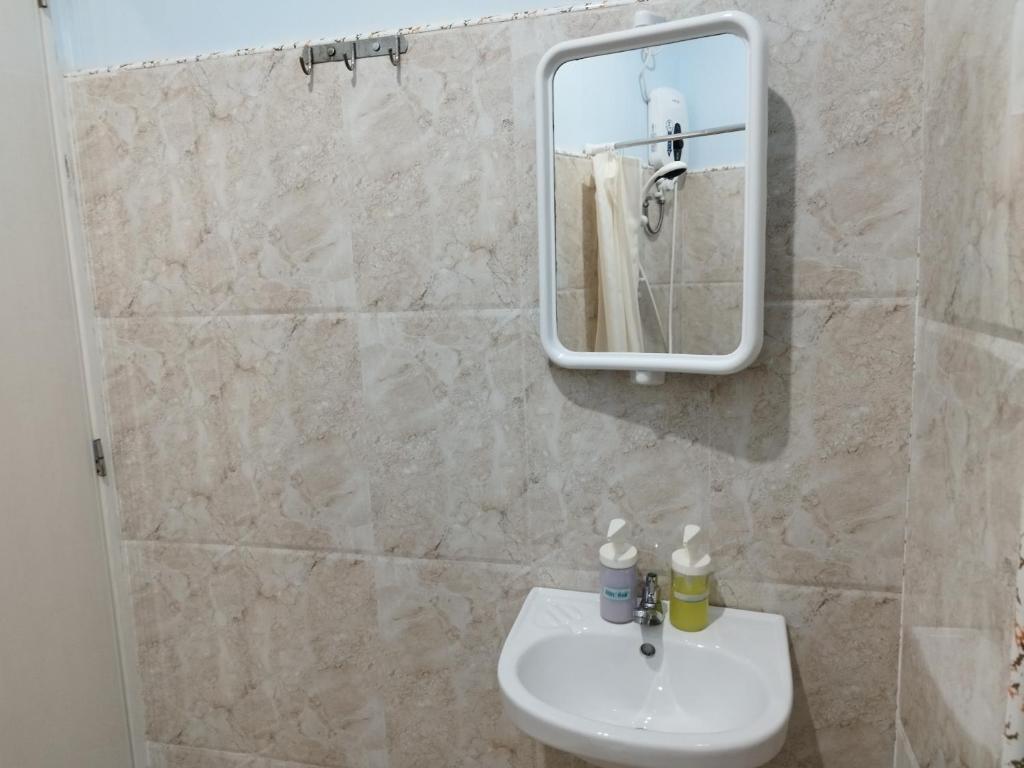 um banheiro com uma pia e um espelho em Ocean View Lodging House em Oslob