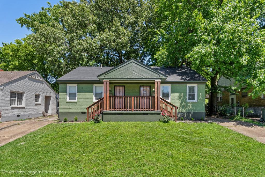 a green house with a deck on a yard at Quiet East Memphis Duplex The Green House in Memphis