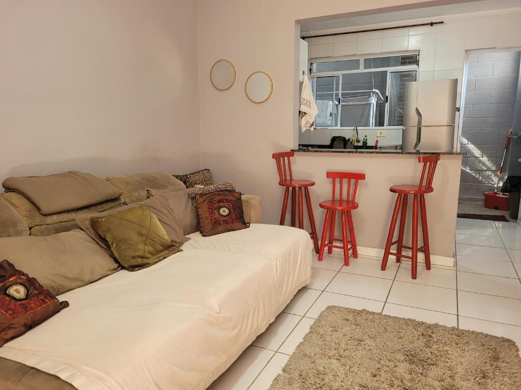 sala de estar con sofá y taburetes rojos en Sobrado de condominio Praia Grande VilaTupi com 2 dormitorio, en Praia Grande