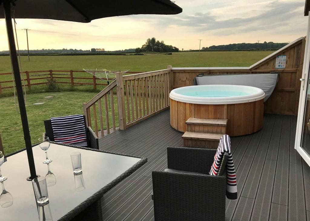 a deck with a hot tub and a table and chairs at Larkrise Farm Lodges in Babcary