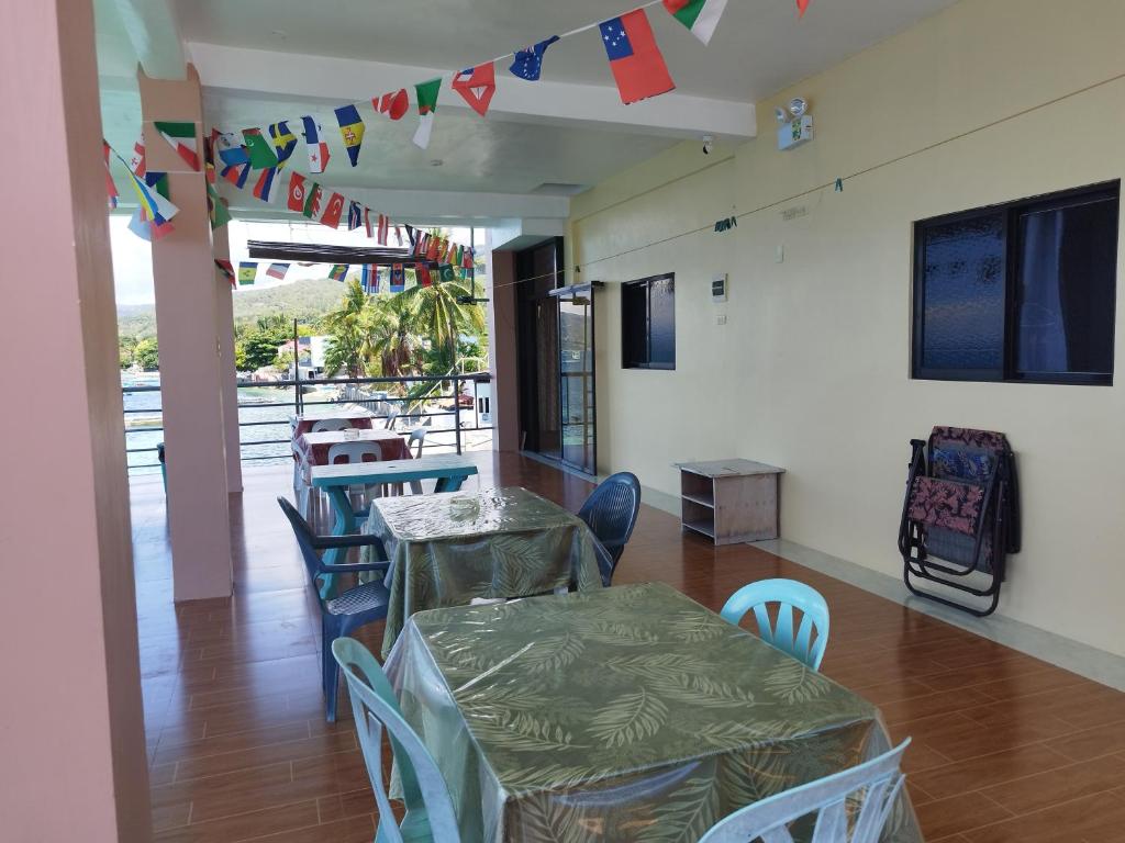 uma sala de jantar com mesas, cadeiras e bandeiras em Ocean View Lodging House em Oslob