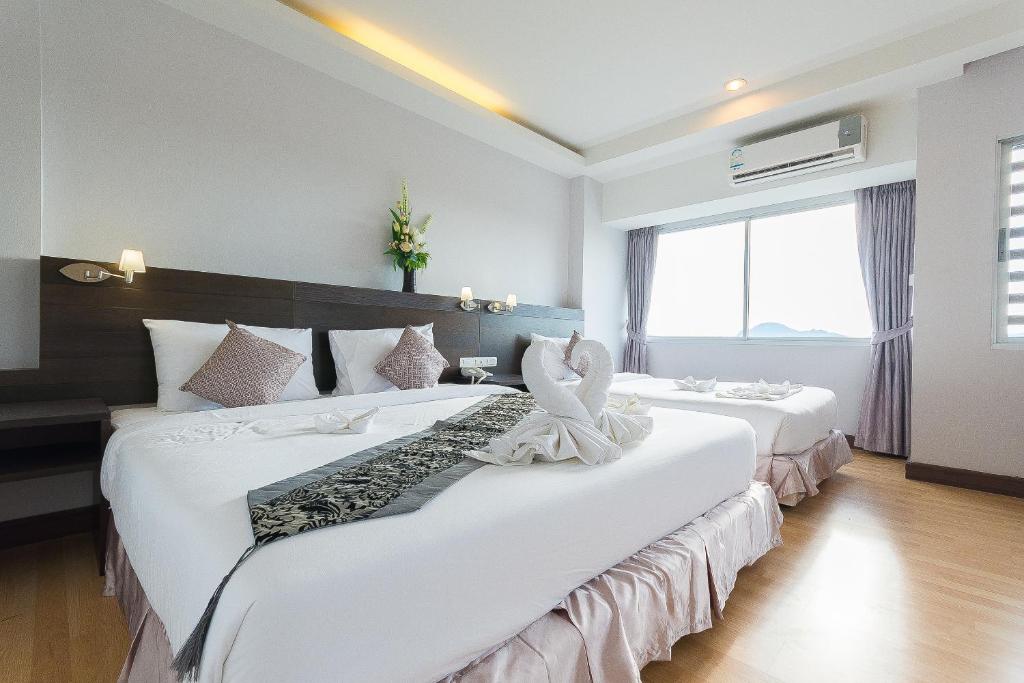 two beds in a hotel room with white sheets at SinKiat Buri Hotel in Satun