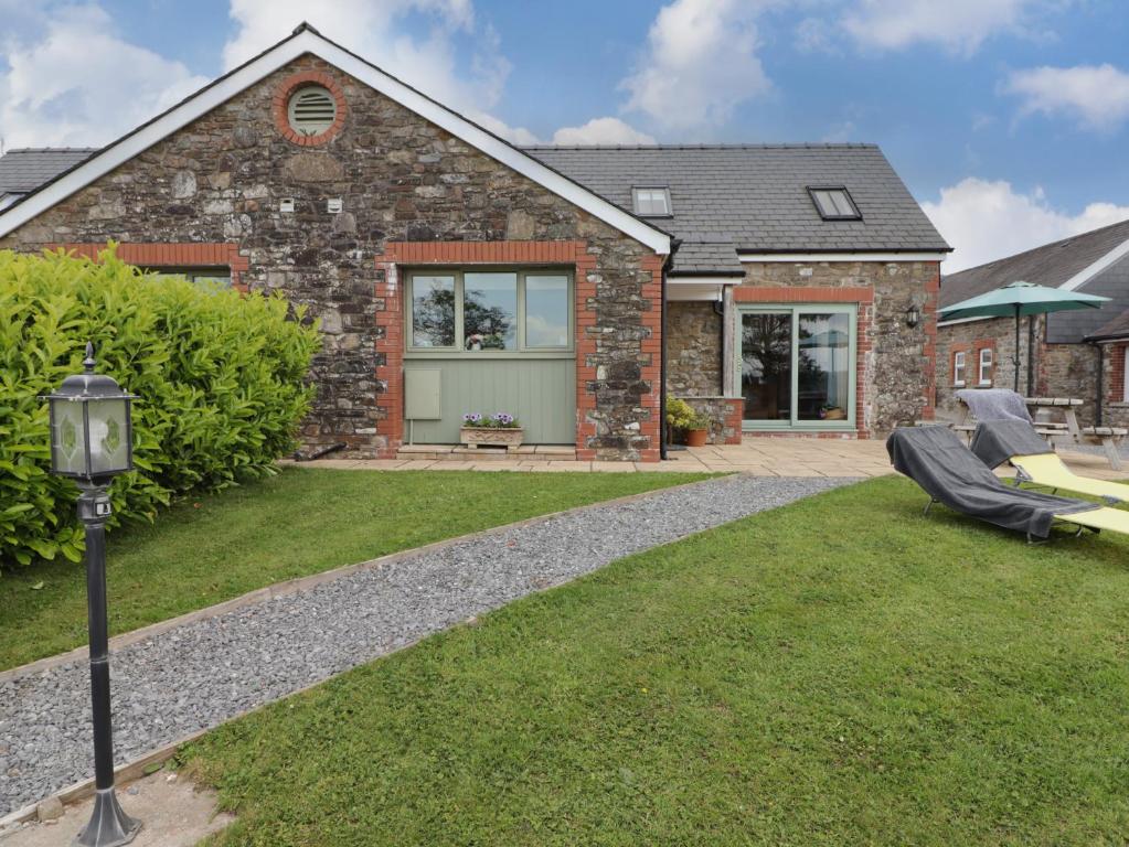 a brick house with a lawn in front of it at Barcud Cottage in Carmarthen