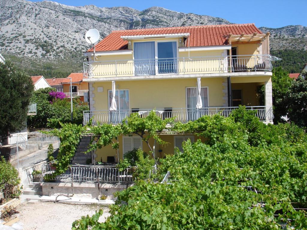 a large yellow house with a balcony and trees at Dominik in Orebić