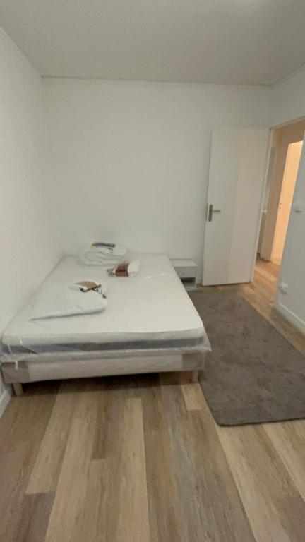 - un lit blanc dans une chambre dotée de parquet dans l'établissement Jules samain, à Lille