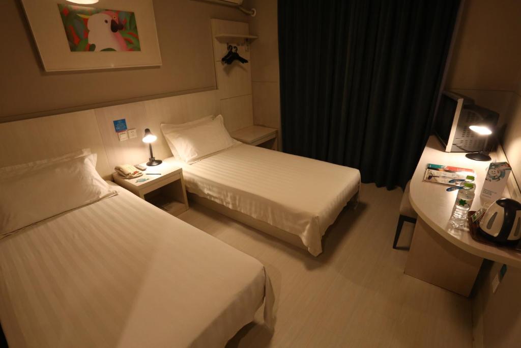 a small hotel room with two beds and a desk at Jinjiang Inn Xiamen Railway Station Dongpu Road in Xiamen