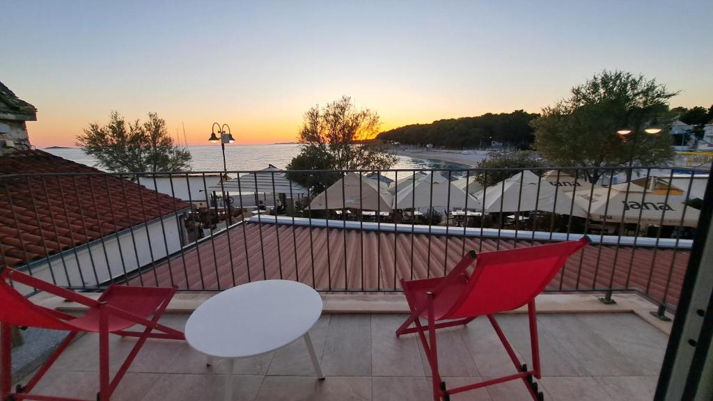 two red chairs and a white table on a balcony at Apartment Primosten Adiomare in Primošten