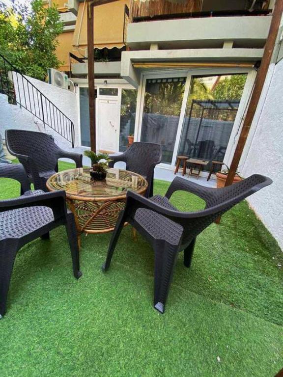 a patio with chairs and a table on the grass at Sea Urban 4 Varkiza in Vari