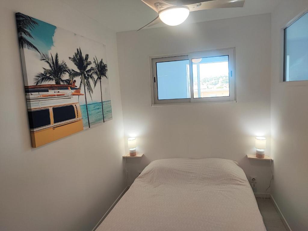 a bedroom with a bed and a window and two lights at Appartement T2 neuf vue mer en bord de mer in Six-Fours-les-Plages