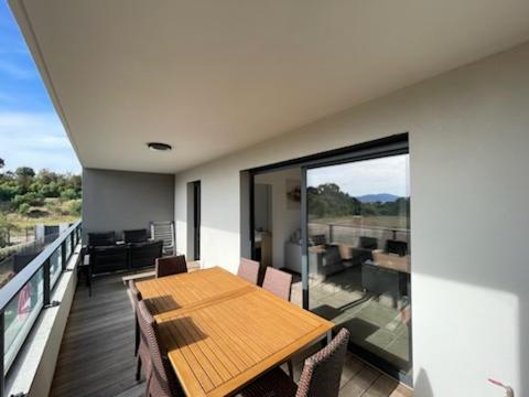 une table et des chaises en bois sur un balcon dans l'établissement T2 Porticcio neuf, à Porticcio