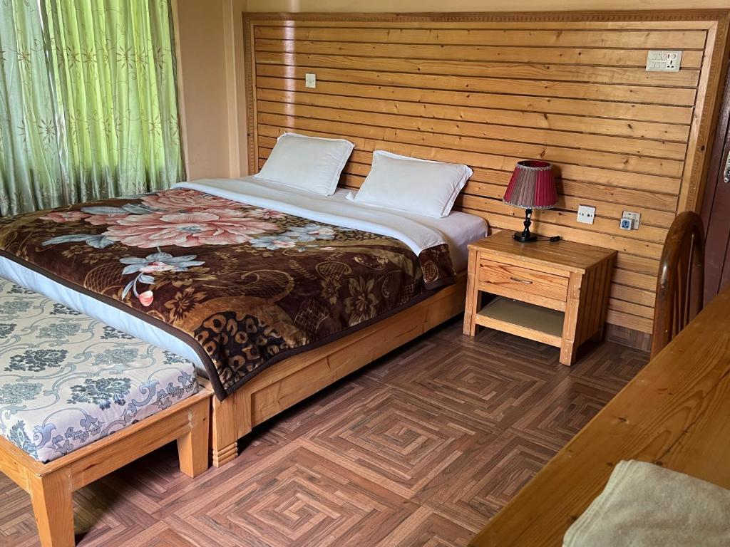 - une chambre avec un lit et une table avec une lampe dans l'établissement Hotel Diplomat, à Pokhara