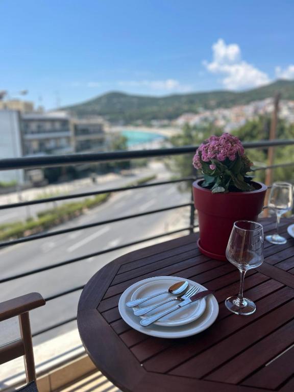a table with a plate and fork and knife on a balcony at Theros Kalamitsa Apartment in Kavála
