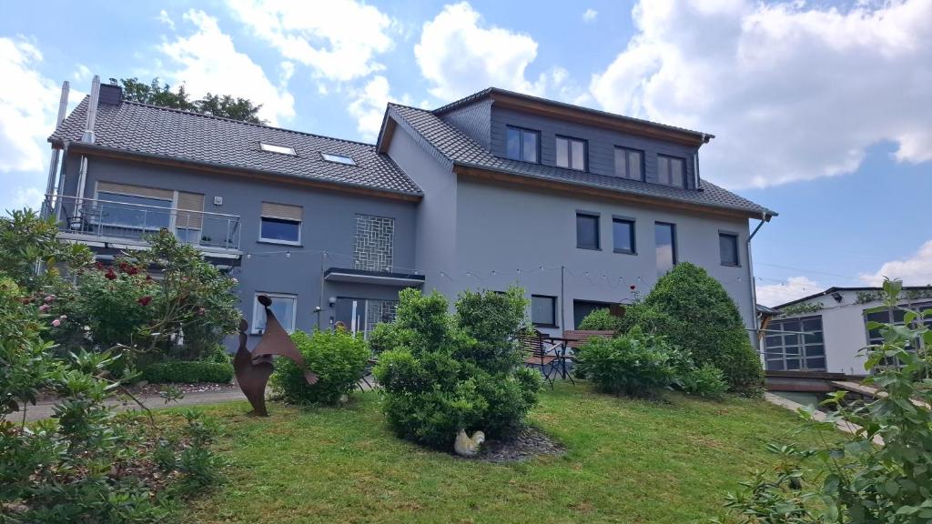 a large white house on a hill with bushes at Ferienwohnung "Auf Plandert" in Riol