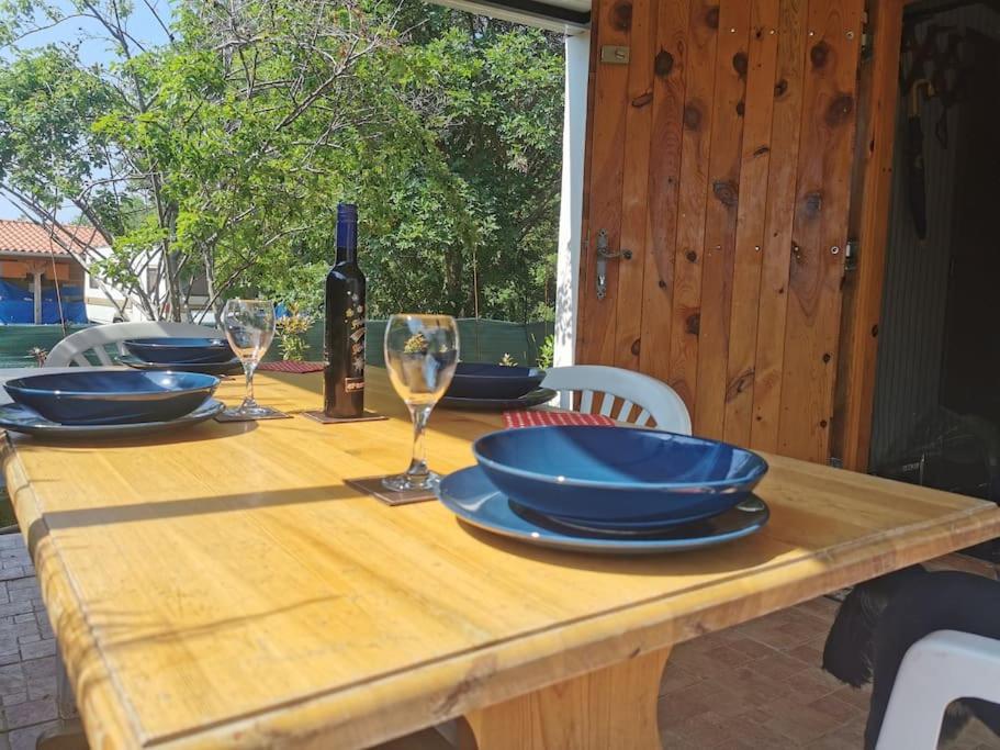 a wooden table with plates and glasses and a bottle of wine at Small Robinson House 250m to the sea in Peroj