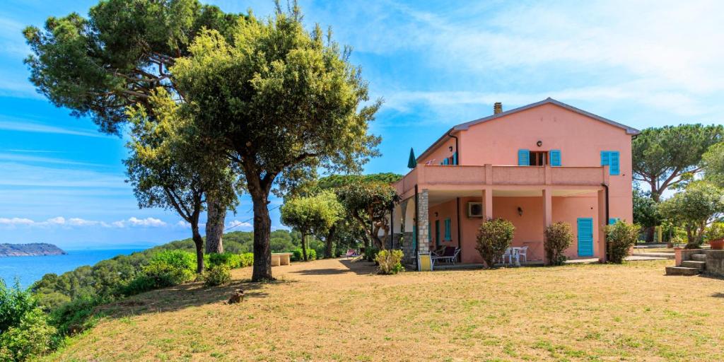 a pink house with a view of the water at Capo Perla Apartments in Capoliveri