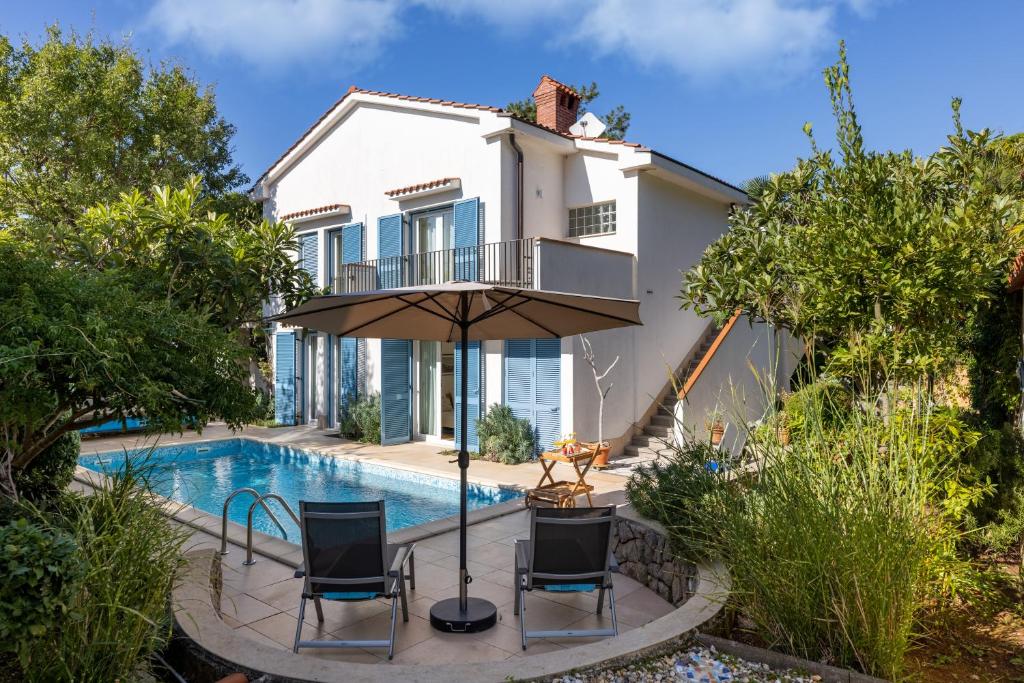 a house with a swimming pool with chairs and an umbrella at Apartman Fana in Njivice