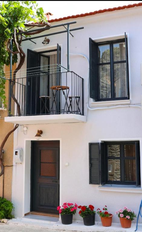 a white building with a balcony and two potted plants at Titinas' in Plomari