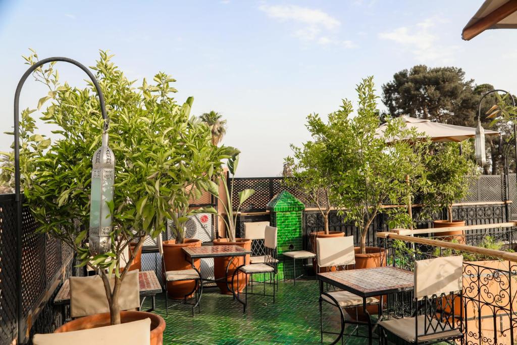 un patio esterno con tavoli, sedie e alberi di Riad Anya & SPA a Marrakech