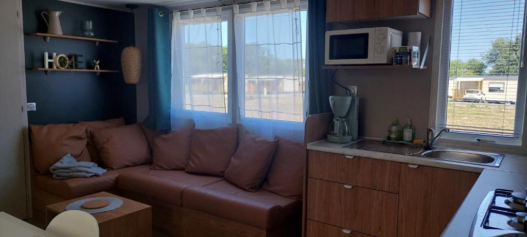 - un salon avec un canapé et un four micro-ondes dans l'établissement Mobil-home bord de mer, à Colleville-sur-Mer