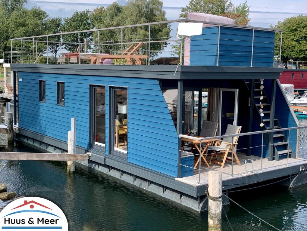a blue house on a boat in the water at Hausboot LUMME - Huus & Meer in Großenbrode-Kai