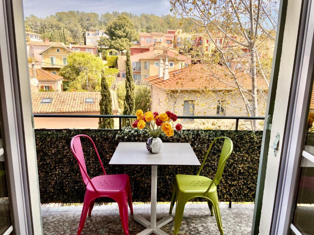 une table avec quatre chaises et un vase de fleurs sur un balcon dans l'établissement St Tropez T2 central, à Saint-Tropez