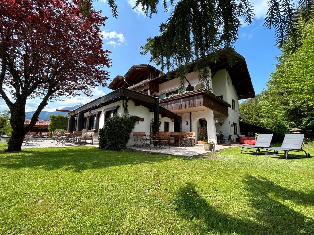a house with a large yard with chairs on the grass at Das Halali - dein kleines Hotel an der Zugspitze in Ehrwald