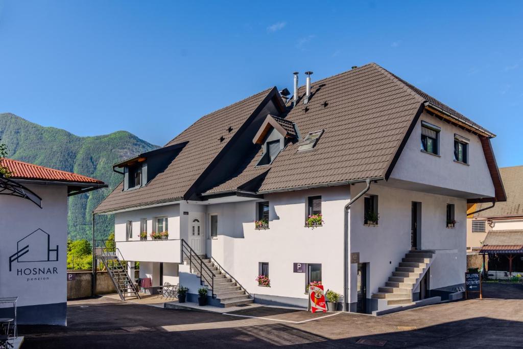 a large white house with a brown roof at Apartmaji Hosnar in Bovec