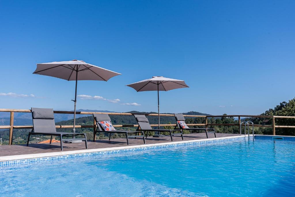 a swimming pool with umbrellas and chairs next to at Casas da Morgadinha - Arais Turismo Rural in Celorico de Basto