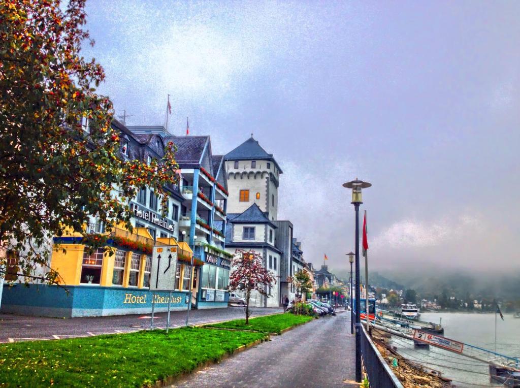 un grand bâtiment situé dans une rue à côté d'une rivière dans l'établissement Hotel Rheinlust, à Boppard