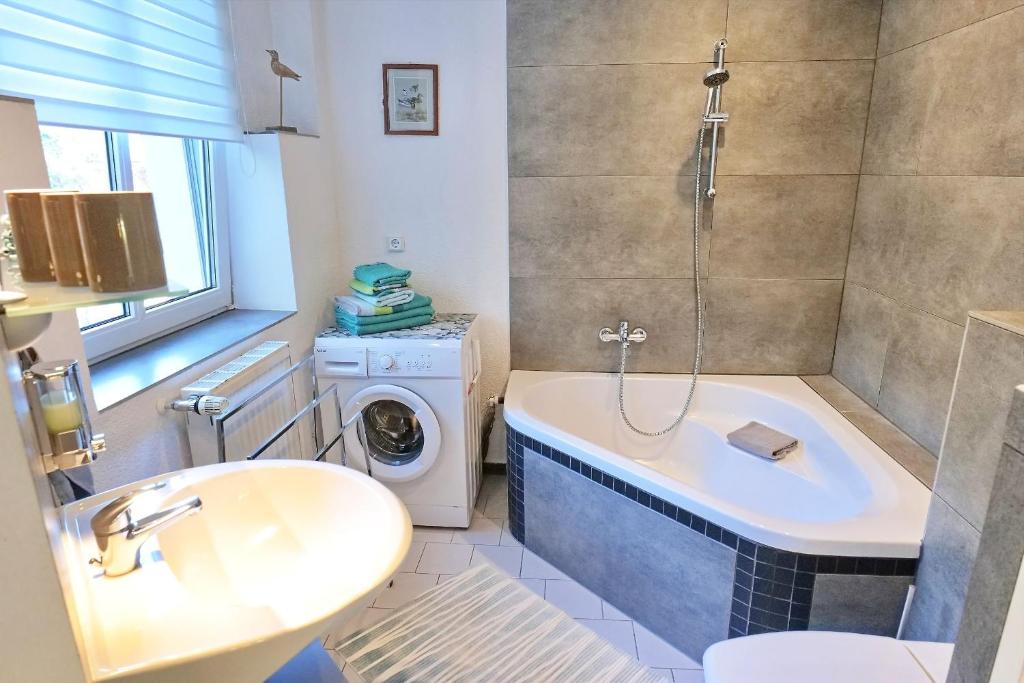 y baño con bañera, lavabo y lavadora. en Altstadt-Fairmietung Erdgeschoss - ABC544, en Wismar