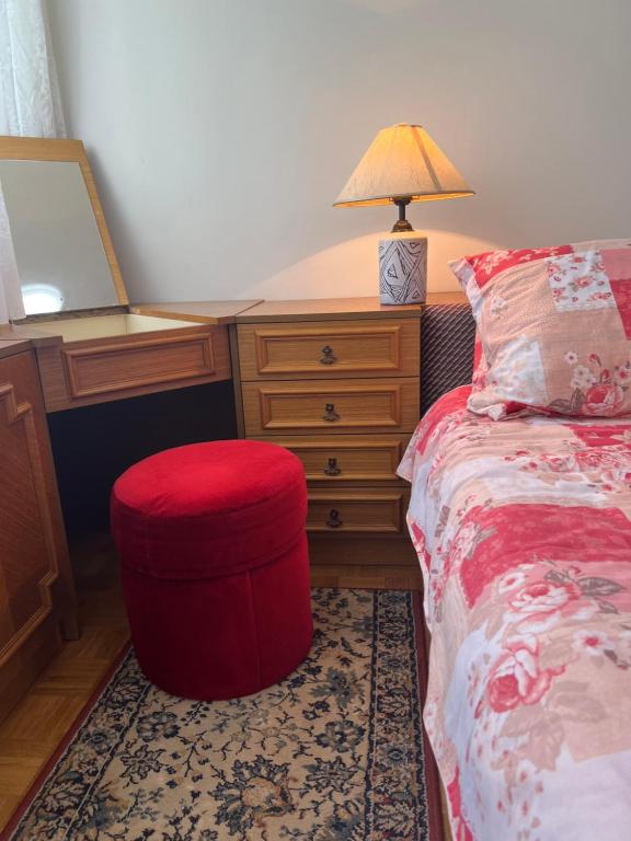 a bedroom with a bed with a red ottoman and a desk at ugodan smjestaj in Velika Gorica