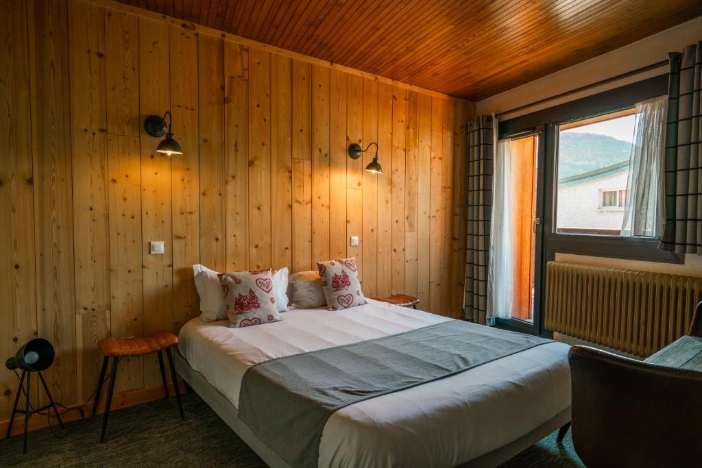 una camera da letto con un grande letto e pareti in legno di Chamois Lodge a Les Deux Alpes