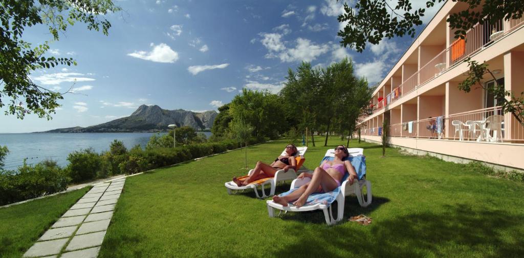 three women sitting in chairs on the grass outside of a hotel at Tourist Settlement Brzet in Omiš