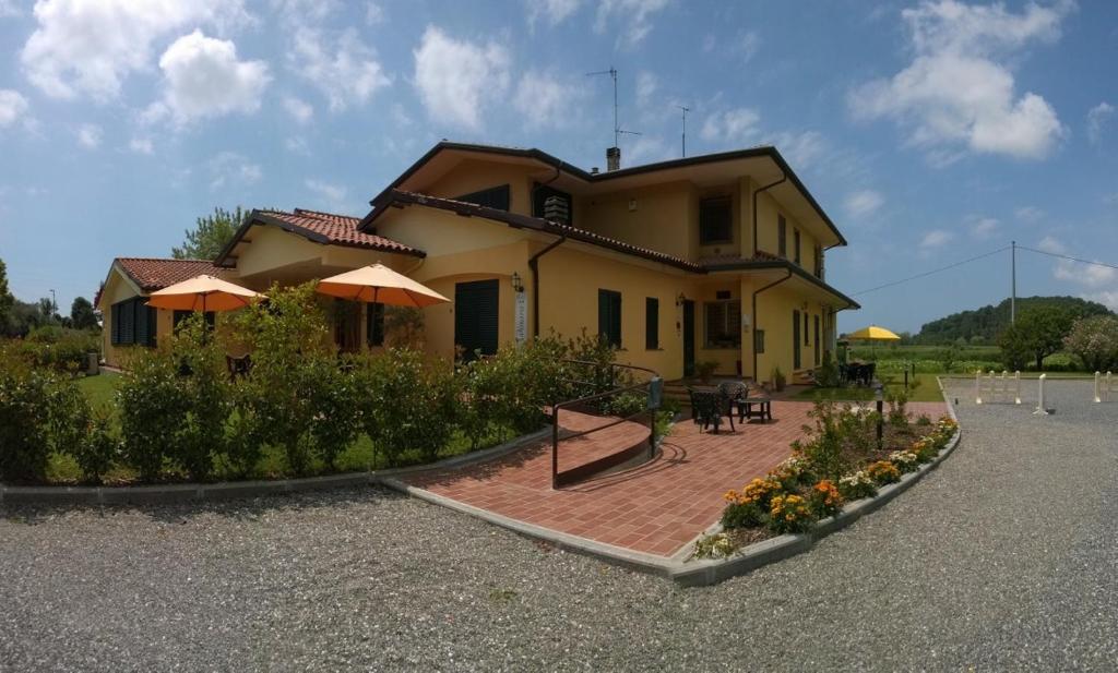 a house with a patio with tables and umbrellas at Cecco di Nara in Massarosa