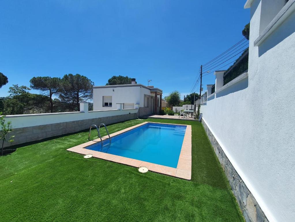 a backyard with a swimming pool and grass at Villa Lloret de Mar 6 Personas in Vidreres
