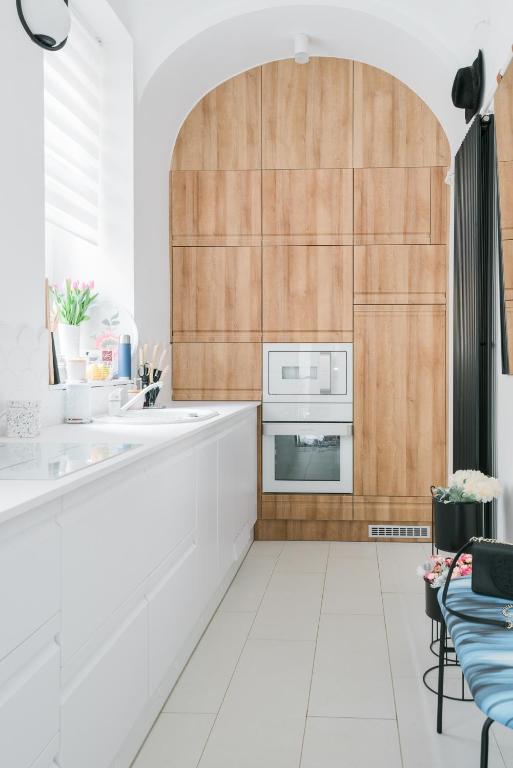 a kitchen with white floors and a wooden wall at S11 Apartman in Debrecen