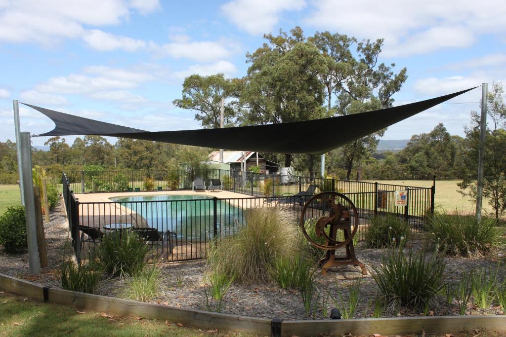 uma lona preta numa cerca ao lado de uma piscina em Woodlane Cottages Hunter Valley em Lovedale