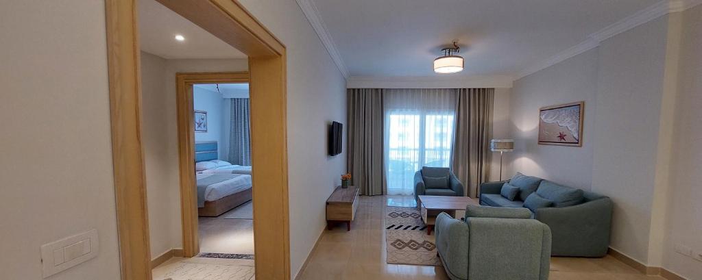 Azur One Eleven Hotel Alamein في العلمين: غرفة معيشة مع أريكة زرقاء وغرفة نوم