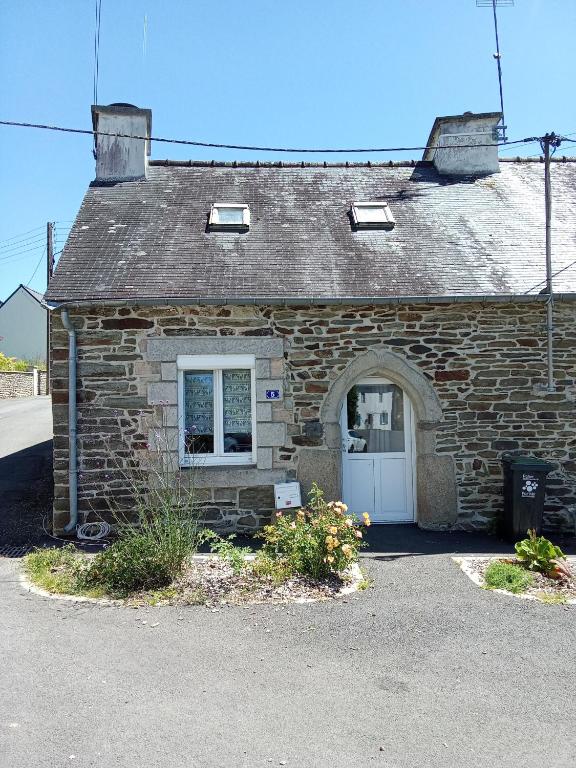 - un bâtiment en pierre avec une porte blanche et une fenêtre dans l'établissement Ti an traõn le petit gîte en cœur de Bretagne, à Carhaix-Plouguer