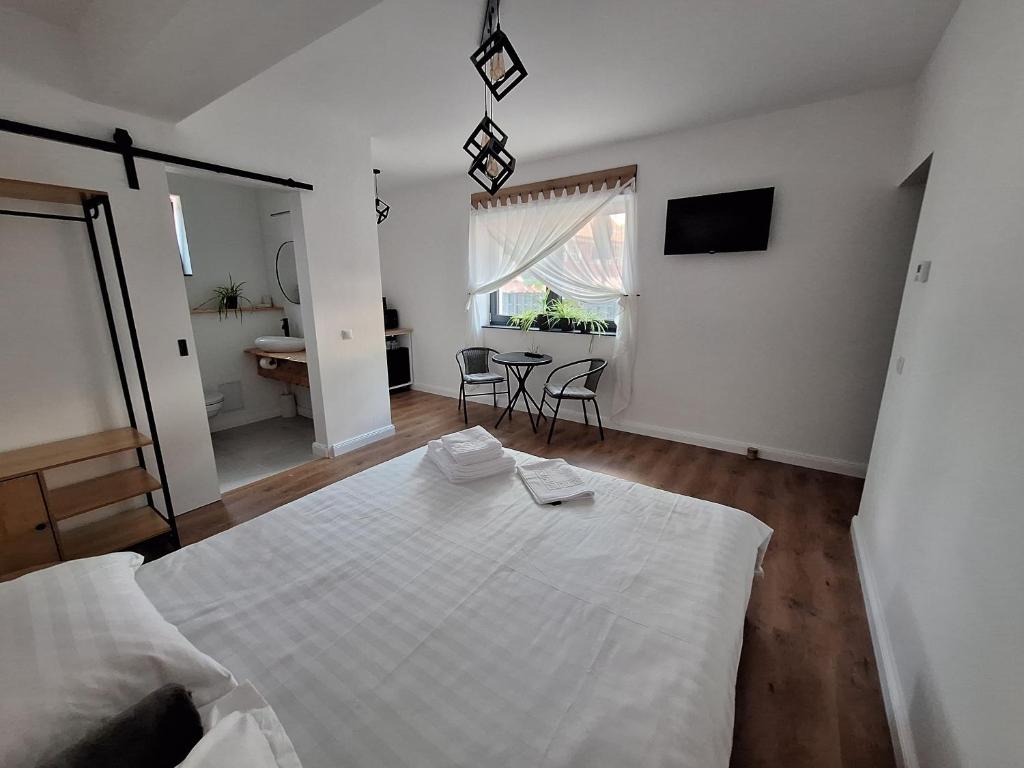 a bedroom with a large white bed and a table at Casa de Caramida in Braşov