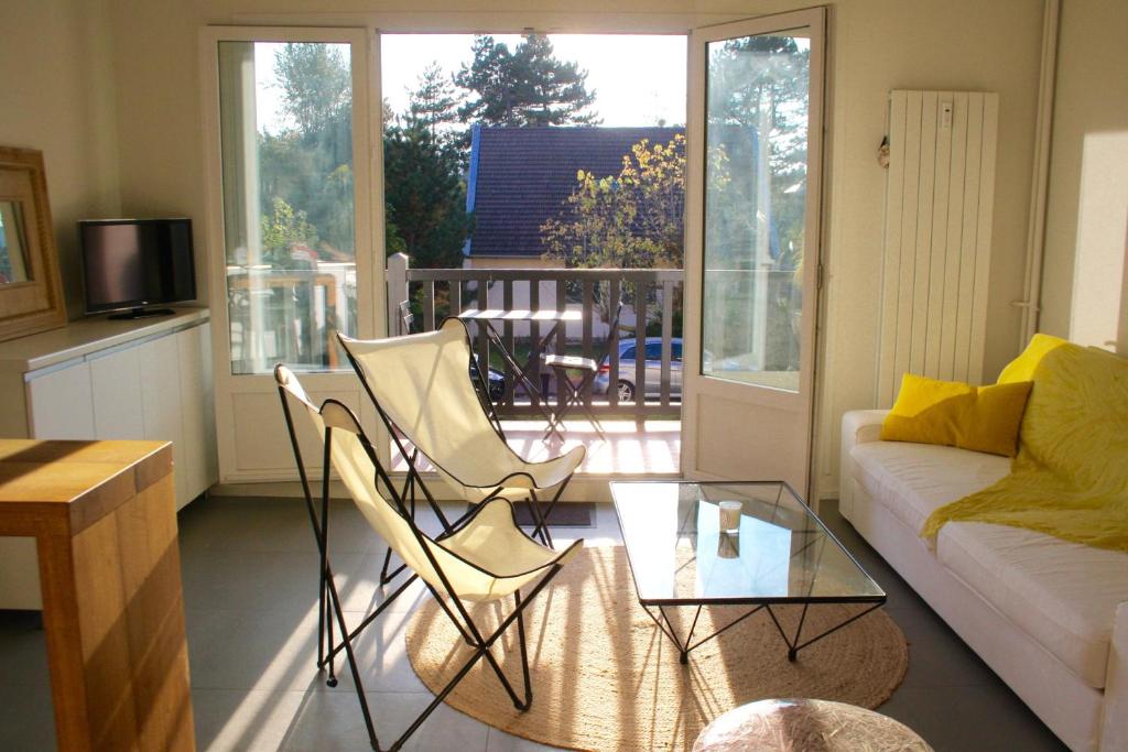 uma sala de estar com um sofá e cadeiras e uma mesa de vidro em Appartement Le Clos de Sablier em Tourgeville