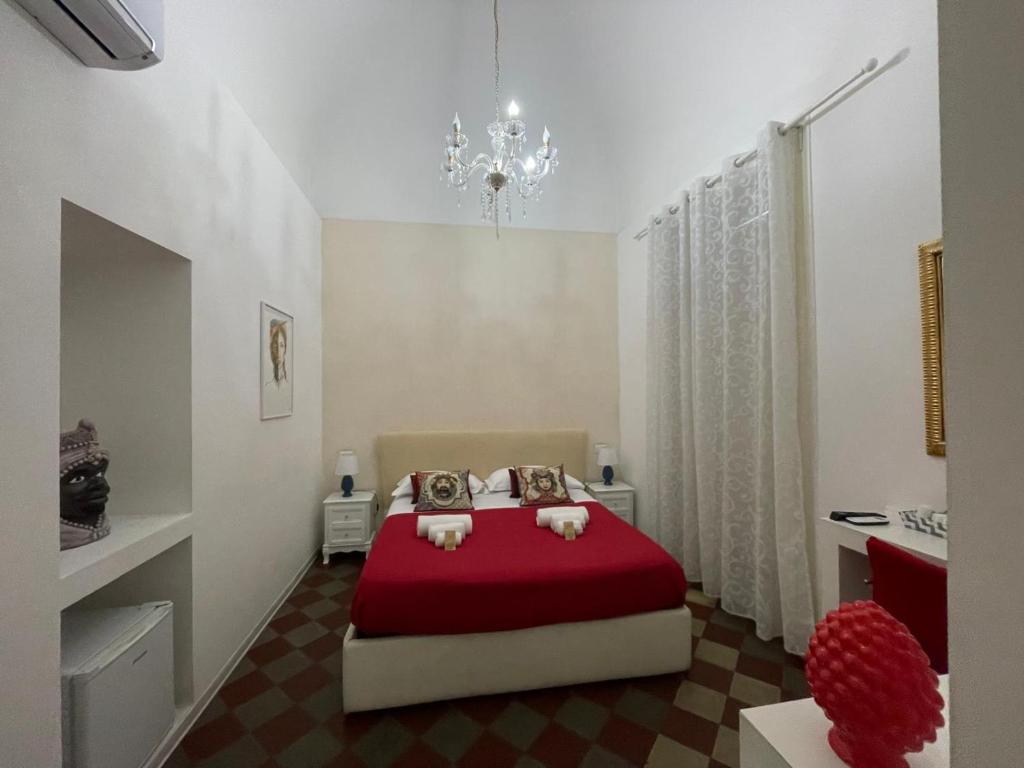 Sleep Inn Catania rooms - Affittacamere في كاتانيا: غرفة نوم بسرير احمر وثريا