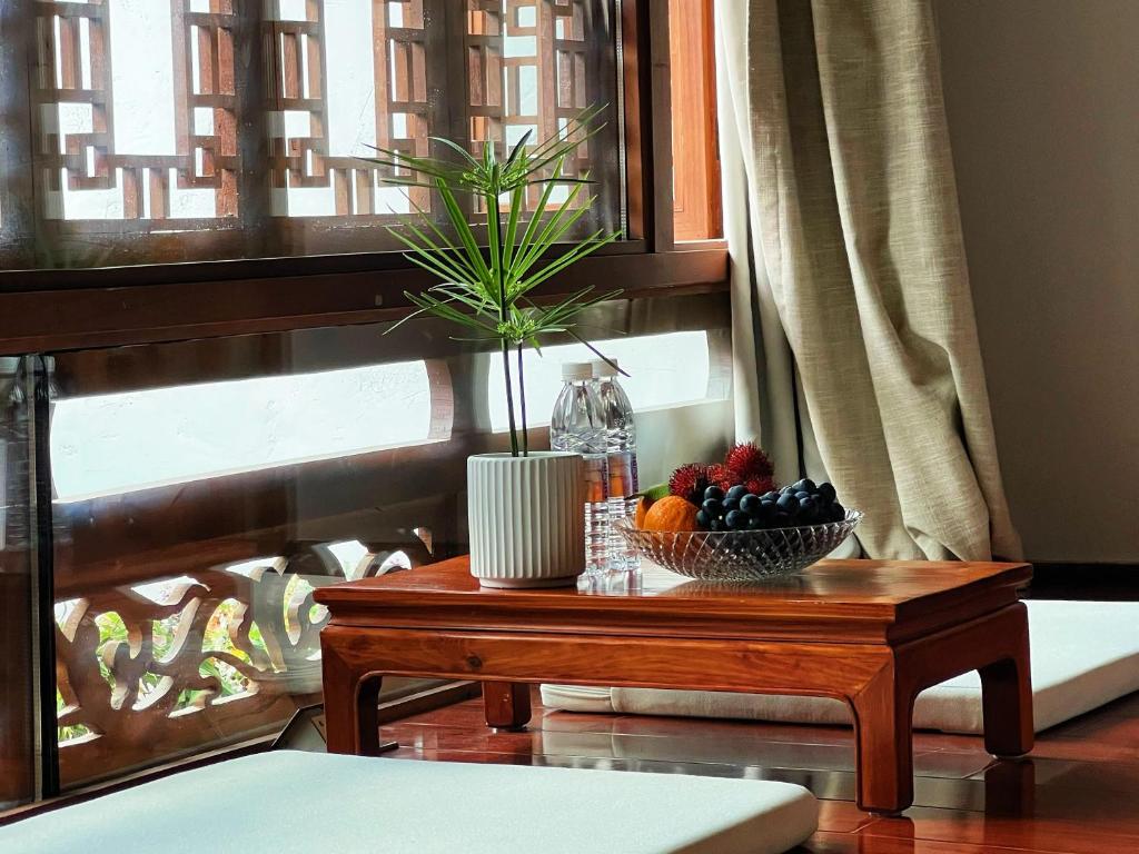 a table with a bowl of fruit and a plant on it at 原乡文苑客栈 in Lijiang