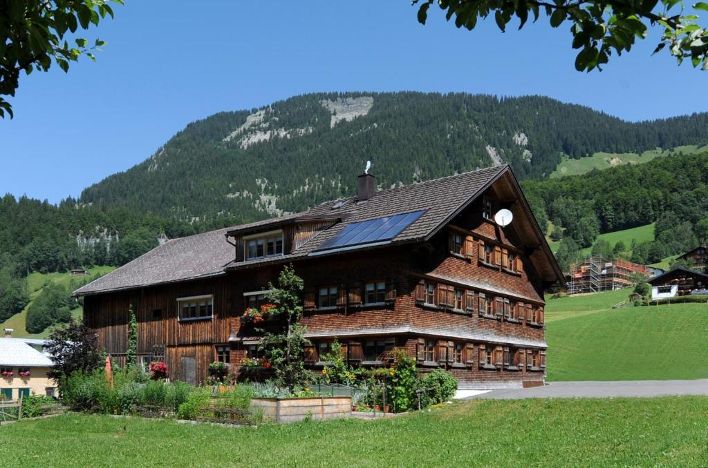 ein großes Holzhaus mit einem Berg im Hintergrund in der Unterkunft Ferienwohnungen Moosbrugger in Au im Bregenzerwald