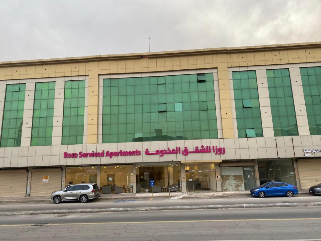 ein großes Gebäude, vor dem Autos parken in der Unterkunft Rosa Aparthotel in Buraida