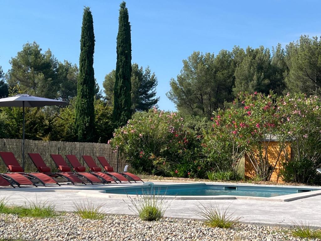 una piscina con tumbonas y sombrilla en Proche Roussillon Luberon villa avec vue, piscine chauffée et climatisation en Gargas