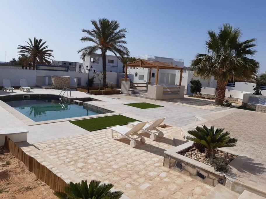 Résidence Mimosas avec piscine et vue de mer في تاجورميس: منزل به مسبح والنخيل