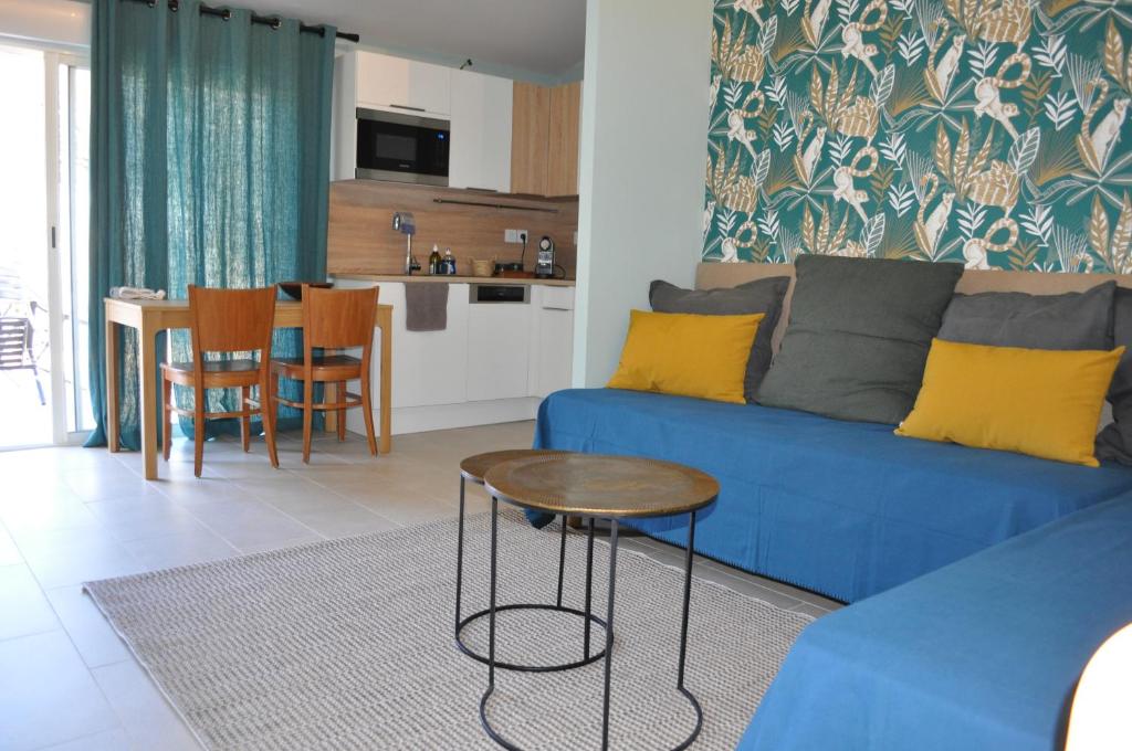 un salon avec un canapé bleu et une table dans l'établissement 7enGarrigue - Charmant deux pièces avec piscine, à Uzès
