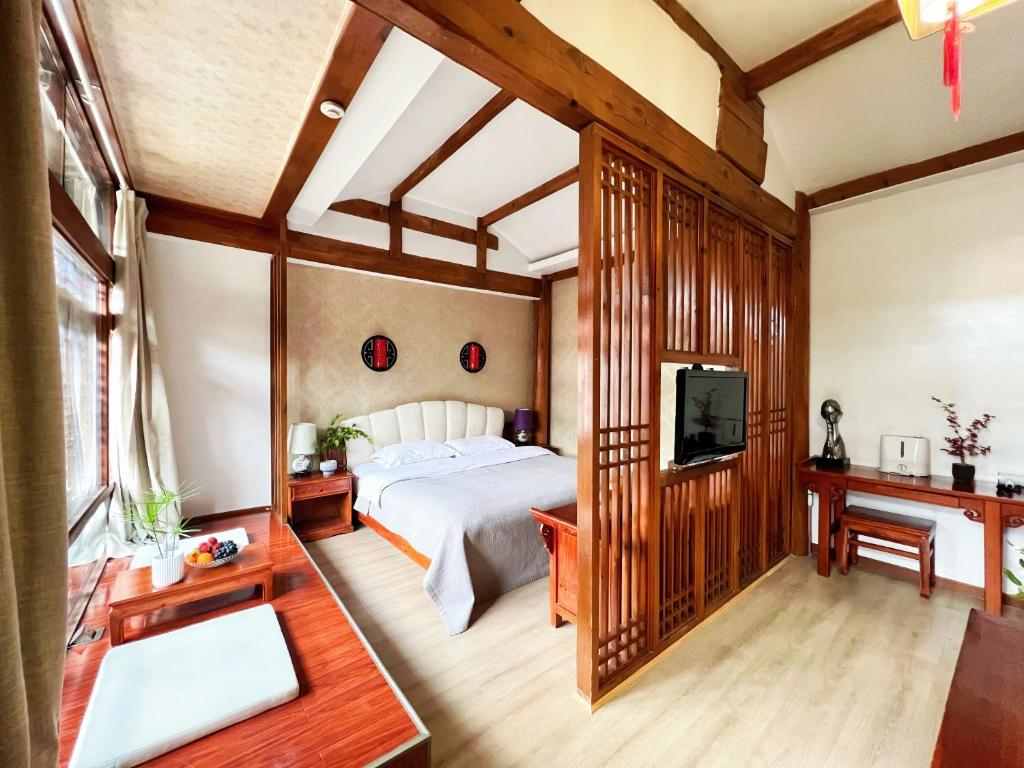 a bedroom with a bed and a flat screen tv at 原乡文苑客栈 in Lijiang